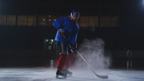 Ein-Hockeyspieler-In-Hockeyuniform-Verlässt-Mit-Einem-Stock-In-Der-Hand-Die-Dunkelheit-Und-Blickt-Direkt-In-Die-Kamera